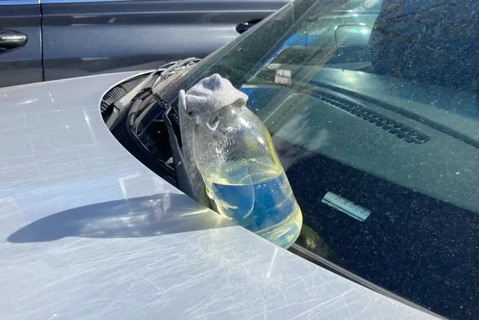 A glass bottle with a rag on a windshield.